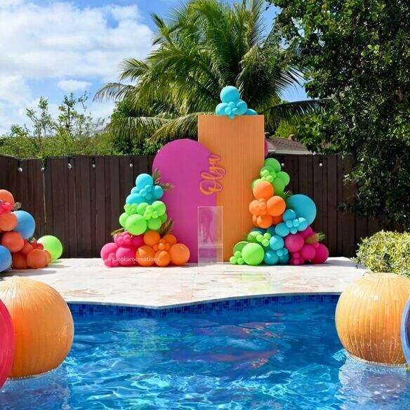Colorful balloon garland and custom backdrop at a summer pool party