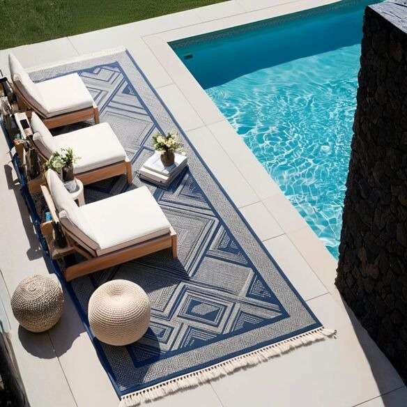 Outdoor rug with cushions and decor near a stylish modern pool setup