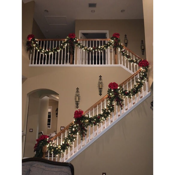 Christmas staircase decoration ideas with garland wrapped around banister and festive entryway